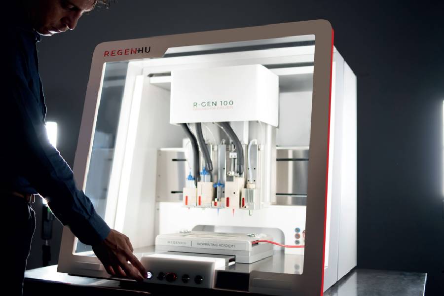 Modelo bioimpressora 3D RegenHU R-gen 100 com homem a carregar num botão em fundo negro