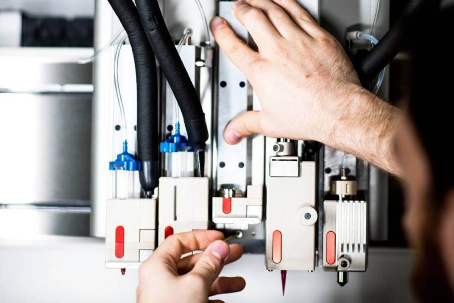 Detalhe da bioimpressora 3D RegenHU R-Gen 100 com mãos de homem